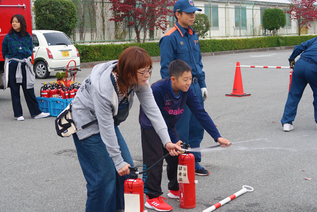 的を狙って消火器を操作する親子