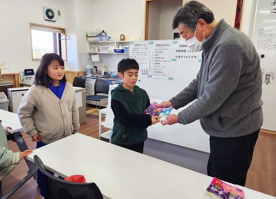 一人ひとりにお菓子を手渡しする拠点スタッフ