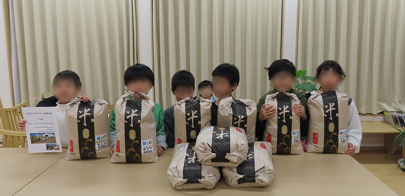 届いた100㎏のお米を前に笑顔の子どもたち