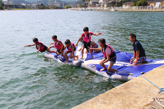海に浮かべた水上マット（浮島）から海に向かって飛び込む子供たち