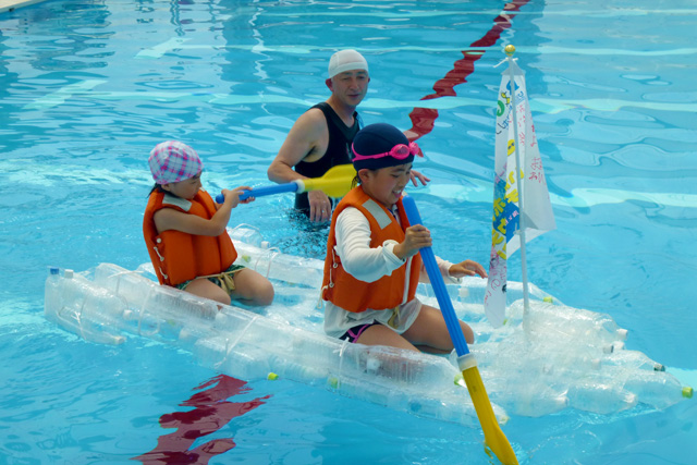 作成したペットボトルカヌーに乗って一生懸命プールで漕いでいます！