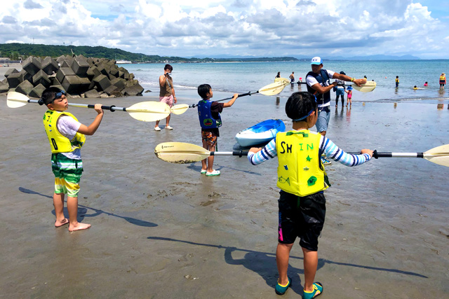 浜辺でオールを実際に持って、カヌーの指導を受ける子供たち