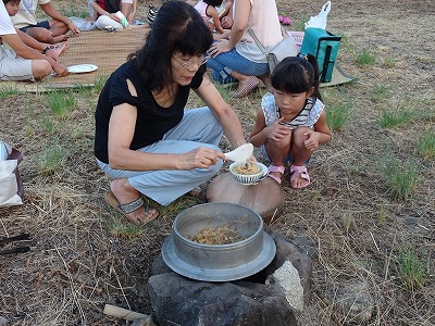 炊き立ての五目飯を給仕するお母さん。かまどの設営や炊き出し作業は男性が行います