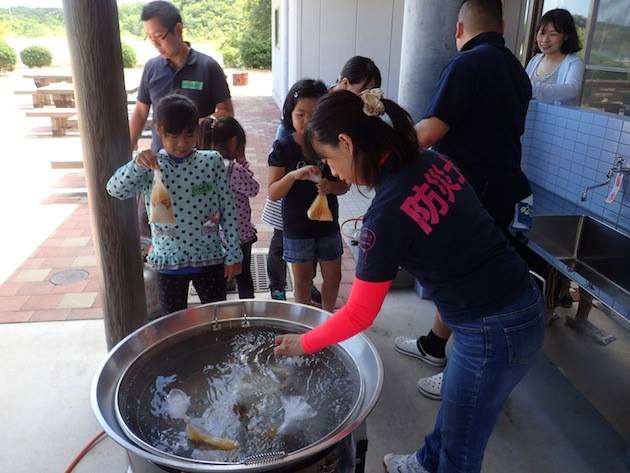 水とお米をビニール袋に入れ、沸騰した鍋のなかに入れてご飯を炊きます。子供たちは興味津々の様子！ 