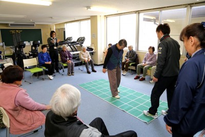  湯前町Ｂ＆Ｇ海洋センター体育館で、頭と身体の両方を使うゲームを楽しむ高齢者の皆さん。スポーツ施設が地域コミュニティの場としても活用されています