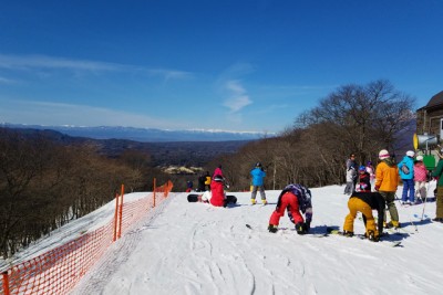 遠くに連なる山々と賑わうゲレンデ