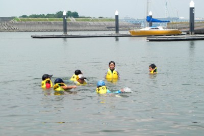 ライフジャケットを着て、海の中で泳いで楽しむ子供たち