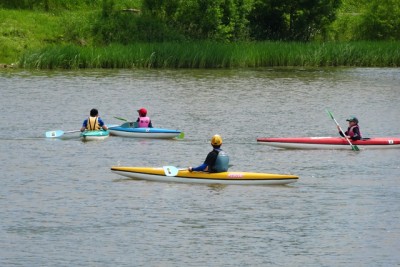 写真は昨年6月。指導実習（カヌー水面指導）、今まで指導されたことを試すチャンス。学校の授業で来ていた子供たちに、陸上や水面でカヌーやローボートの指導。水面で子供にカヌーを指導しているところ。指導しながら監視もする