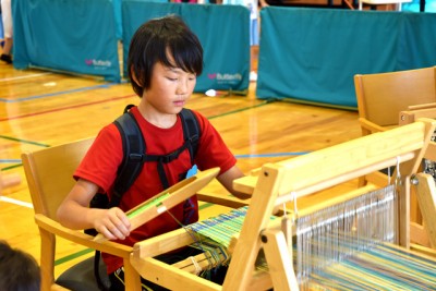 機織り機に真剣に向かっている少年