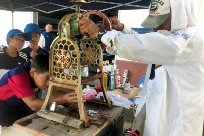 昔ながらのかき氷機の下で、バランスよく入るようにガラスの容器を回す男の子