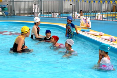 浅い幼児用プールで泳ぎを習う子供たち
