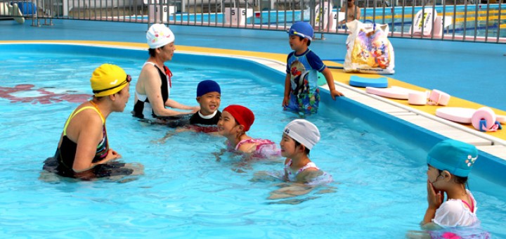 浅い幼児用プールで泳ぎを習う子供たち