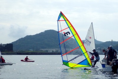 奇跡のコラボ！　風のない日はウィンドサーフィンも大苦戦。　心配そうに見守るカヌー、ヨット２人組、レーザー