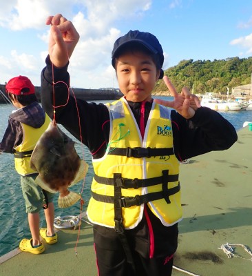 釣りあげたカワハギを見せながら笑顔でピースする女の子