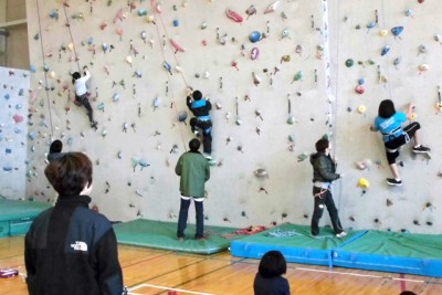 室内のクライミング用の壁をよじ登る子供たち