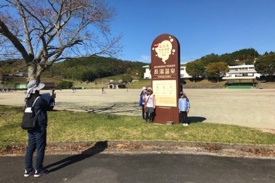 長湯温泉の看板と記念撮影をする参加者の方々