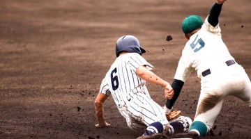 ベースに向かって走りこむ選手にタッチする野手