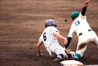 ベースに向かって走りこむ選手にタッチする野手