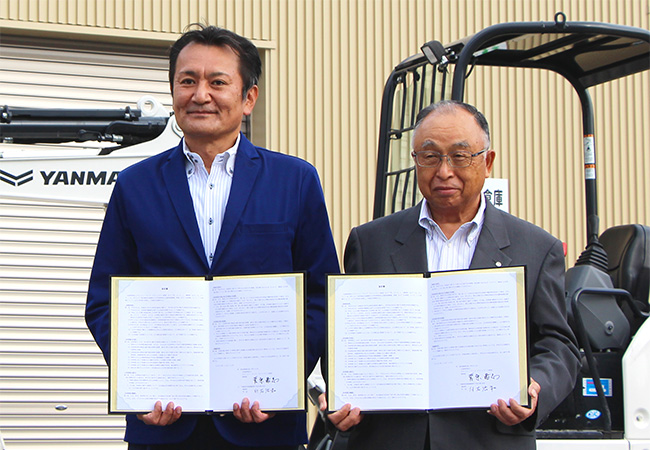 調印書を掲げる菅原理事長（左）と白石町長（右）