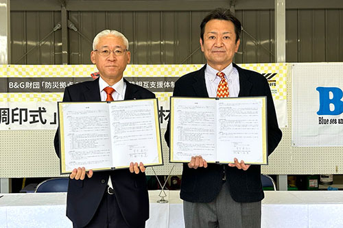 調印書を掲げる相川町長（写真左）と菅原理事長（写真右）