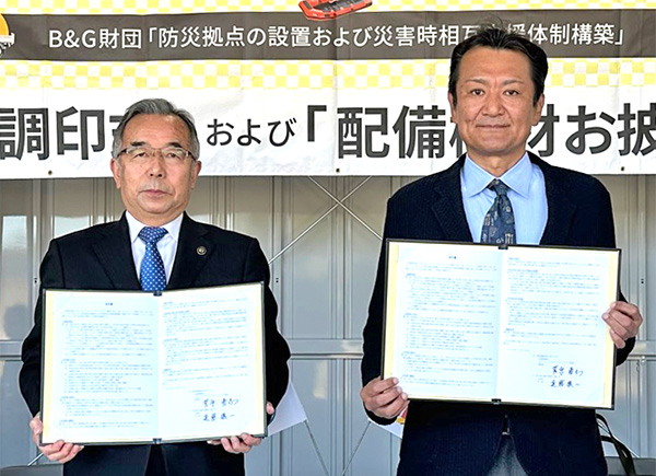 調印書を掲げる遠藤市長（写真左）と菅原理事長（写真左）
